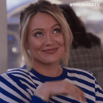 A Woman Wearing A Blue And White Striped Sweater Is Smiling And Looking Up GIF
