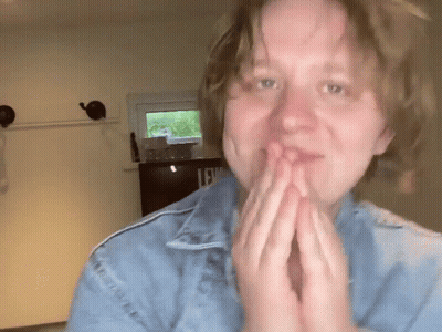 A Woman Wearing A Blue Denim Jacket With The Letter L On It GIF