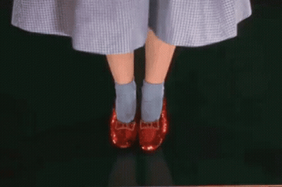 A Woman Wearing A Blue Dress And Red Shoes Is Standing On A Green Surface . GIF