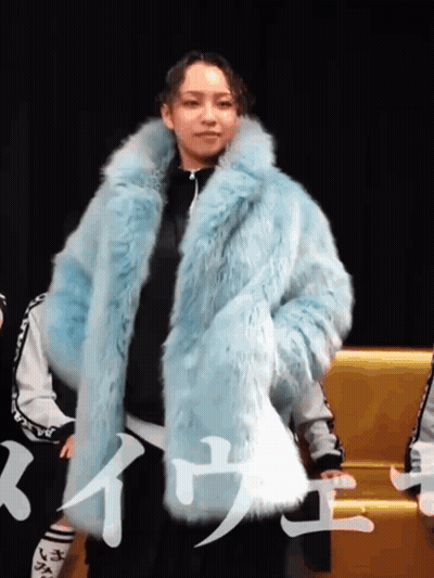 A Woman Wearing A Blue Fur Coat With Chinese Writing On The Bottom GIF