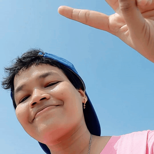 A Woman Wearing A Blue Hat And A Pink Shirt Is Making A Funny Face GIF