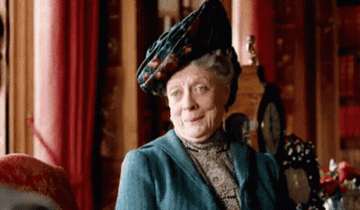A Woman Wearing A Blue Jacket And A Hat Is Sitting In A Chair . GIF