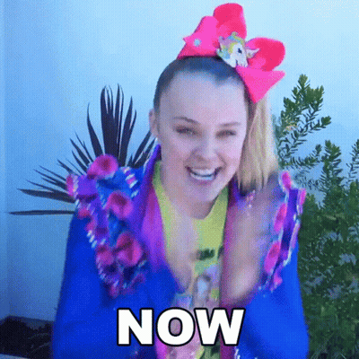 A Woman Wearing A Blue Jacket And A Pink Bow On Her Head Says " Now " GIF