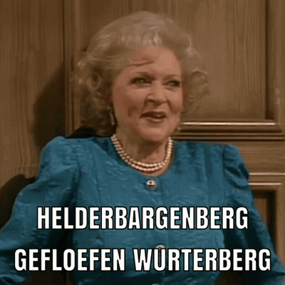 A Woman Wearing A Blue Jacket And Pearls Says Helderbergenberg Gefloeffen Wurtenberg GIF