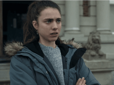 A Woman Wearing A Blue Jacket With A Fur Hood Is Standing In Front Of A Building GIF
