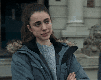 A Woman Wearing A Blue Jacket With A Fur Hood Is Standing In Front Of A Building GIF