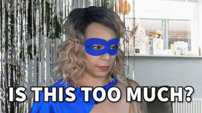 A Woman Wearing A Blue Mask With The Words Is This Too Much Behind Her GIF