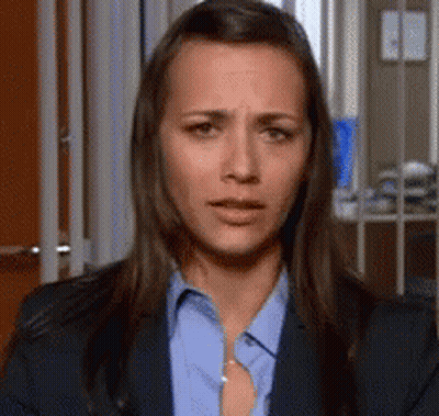A Woman Wearing A Blue Shirt And A Suit Is Making A Sad Face . GIF