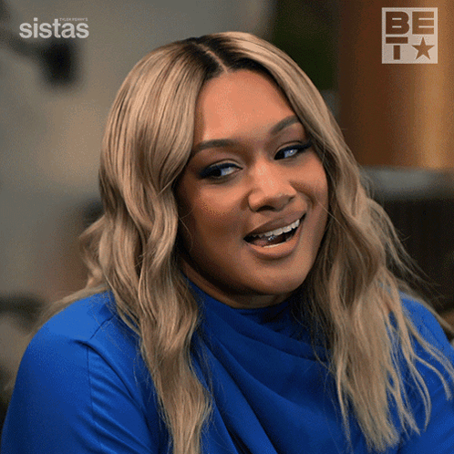 A Woman Wearing A Blue Shirt Is Smiling In Front Of A Be Tv Logo GIF