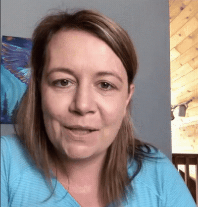 A Woman Wearing A Blue Shirt Is Smiling In Front Of A Painting On The Wall . GIF