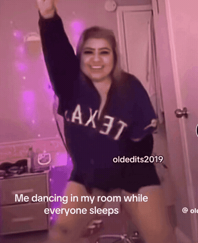 A Woman Wearing A Blue Shirt That Says Ax37 Is Dancing In A Room While Everyone Sleeps GIF
