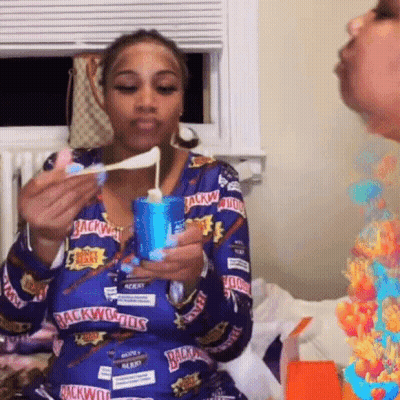 A Woman Wearing A Blue Shirt That Says Backwoods On It Is Eating Something GIF