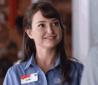 A Woman Wearing A Blue Shirt With A Name Tag That Says Lily GIF