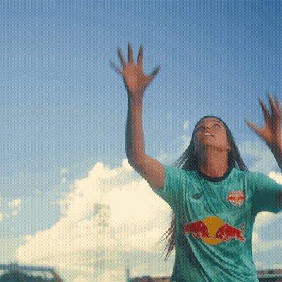 A Woman Wearing A Blue Shirt With A Red Bull On The Front GIF