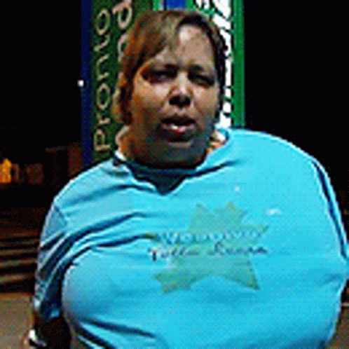 A Woman Wearing A Blue Shirt With A Star On It Is Standing In Front Of A Vending Machine . GIF