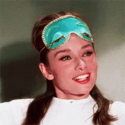 A Woman Wearing A Blue Sleep Mask Is Smiling And Looking At The Camera . GIF