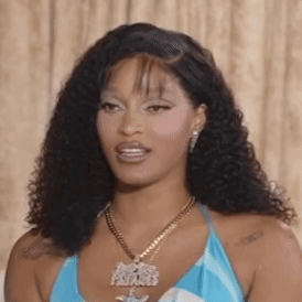 A Woman Wearing A Blue Top And A Gold Necklace Is Looking At The Camera . GIF