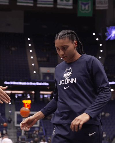 A Woman Wearing A Blue Uconn Shirt Reaches Out To Shake Someone 'S Hand GIF