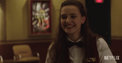 A Woman Wearing A Bow Tie Is Smiling In Front Of A Netflix Logo GIF