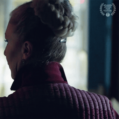 A Woman Wearing A Braided Bun Is Standing In Front Of A Sign That Says Atlanta Short Film Festival GIF