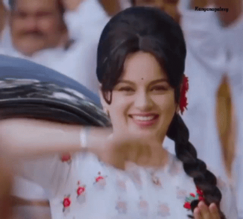 A Woman Wearing A Braided Ponytail Is Smiling And Holding A Bunch Of Trash Bags . GIF