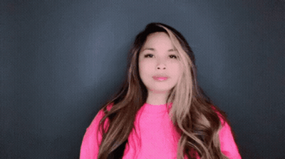 A Woman Wearing A Bright Pink Sweater Is Making A Funny Face GIF