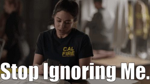 A Woman Wearing A Cal Fire Shirt Sits At A Desk GIF