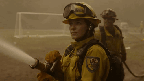 A Woman Wearing A Cal Fire Uniform Holds A Hose GIF