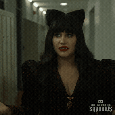 a woman wearing a cat ear wig from fx 's what we do in the shadows is making a funny face