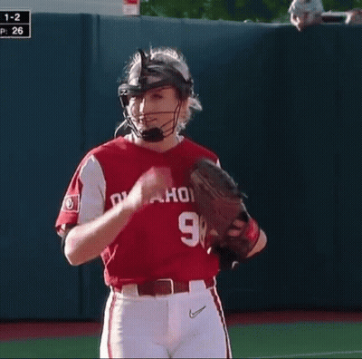 A Woman Wearing A Catcher 'S Helmet And Glove Stands On The Field GIF