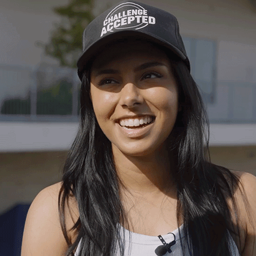 A Woman Wearing A Challenge Accepted Hat Smiles GIF