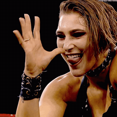 A Woman Wearing A Choker And A Ring On Her Finger Is Smiling And Making A Funny Face GIF