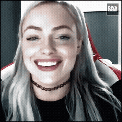 A Woman Wearing A Choker Is Smiling In Front Of A Diva Banner GIF