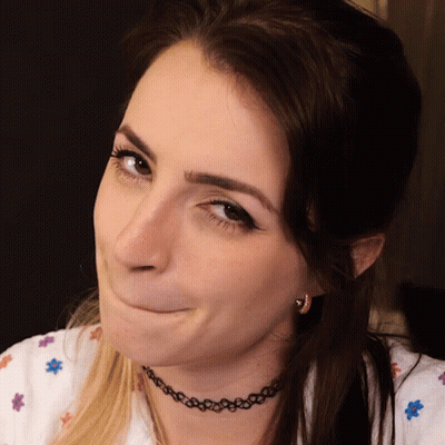 A Woman Wearing A Choker Necklace And Earrings Makes A Funny Face GIF
