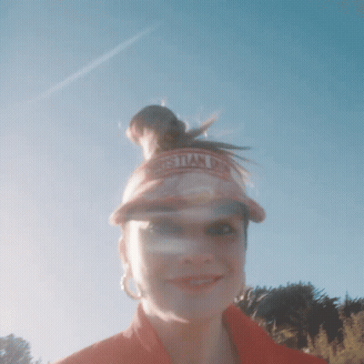 A Woman Wearing A Christian Dior Visor Stands In Front Of A Blue Sky GIF
