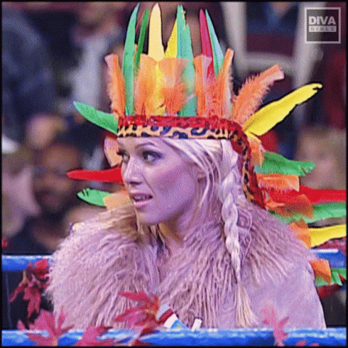 A Woman Wearing A Colorful Feathered Headdress With Diva Written On The Bottom Left GIF