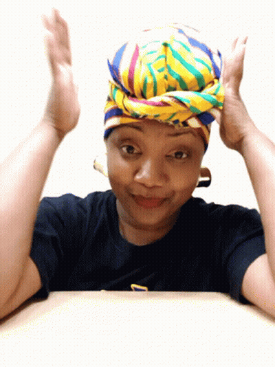 A Woman Wearing A Colorful Head Scarf And A Black Shirt With The Letter T On It GIF