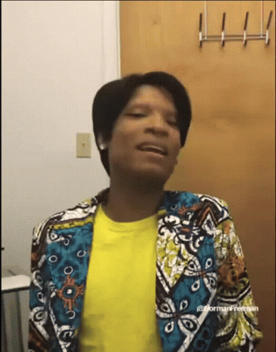 A Woman Wearing A Colorful Jacket And A Yellow Shirt Is Making A Funny Face . GIF