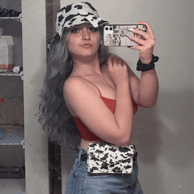 A Woman Wearing A Cow Print Hat Takes A Selfie With Her Phone GIF