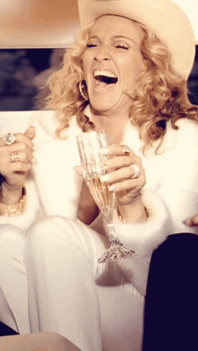 A Woman Wearing A Cowboy Hat Is Holding A Glass Of Champagne GIF