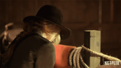 A Woman Wearing A Cowboy Hat Is Standing Next To A Netflix Logo GIF