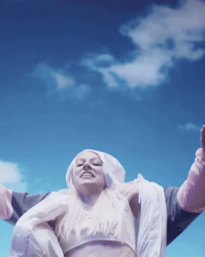 A Woman Wearing A Crop Top And A Hooded Jacket With The Word Nike On It GIF