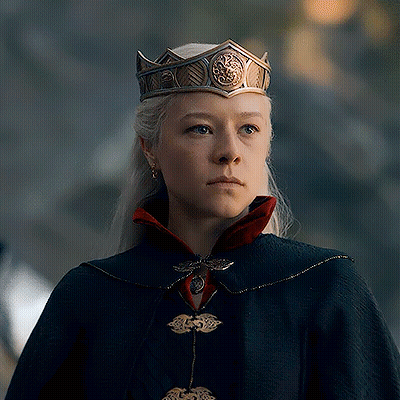 A Woman Wearing A Crown And A Cape Is Looking At The Camera GIF