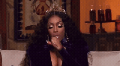 A Woman Wearing A Crown Is Sitting On A Couch Talking On A Cell Phone . GIF