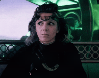 A Woman Wearing A Crown On Her Head Is Sitting In A Dark Room . GIF