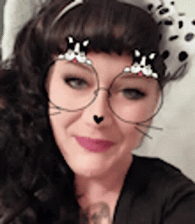 A Woman Wearing A Dalmatian Hat And Glasses With A Cat Face Filter On Her Face . GIF
