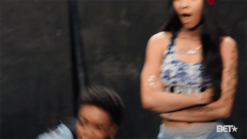 A Woman Wearing A Denim Jacket Is Smiling With The Bet Logo Behind Her GIF