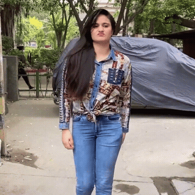 A Woman Wearing A Denim Shirt And Jeans Making A Funny Face GIF