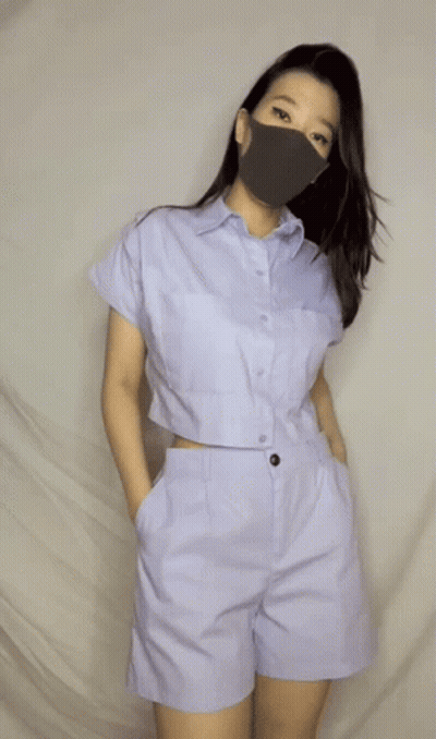 A Woman Wearing A Face Mask And A Crop Top GIF