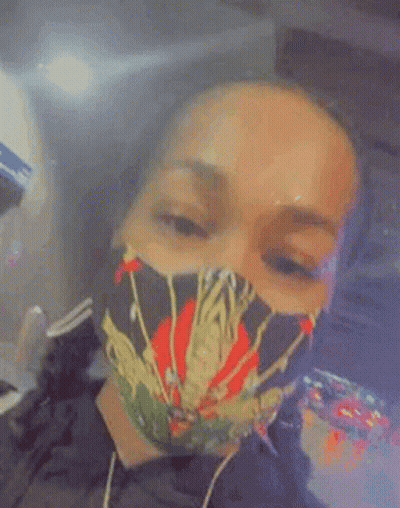 A Woman Wearing A Face Mask With A Spider On It Is Smoking A Cigarette . GIF